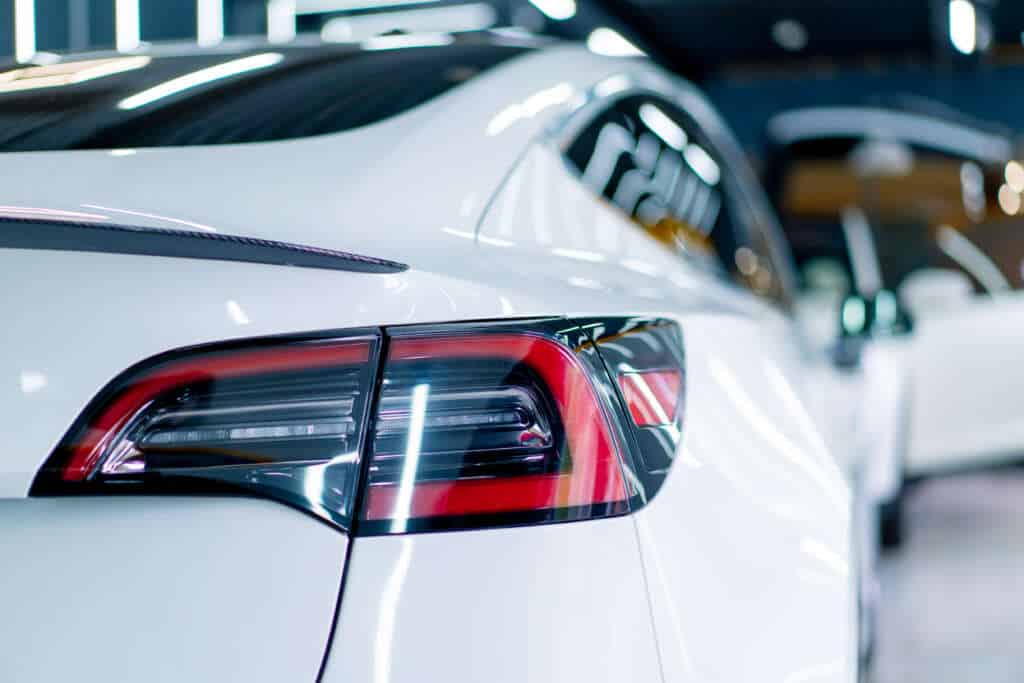 Exterior Car Detailing Near Me: Detailer Hand Cleaning The Bumper And Taillight Of A White Car